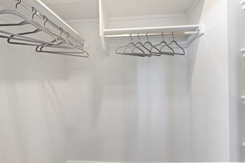 A white closet with clothes hangers.